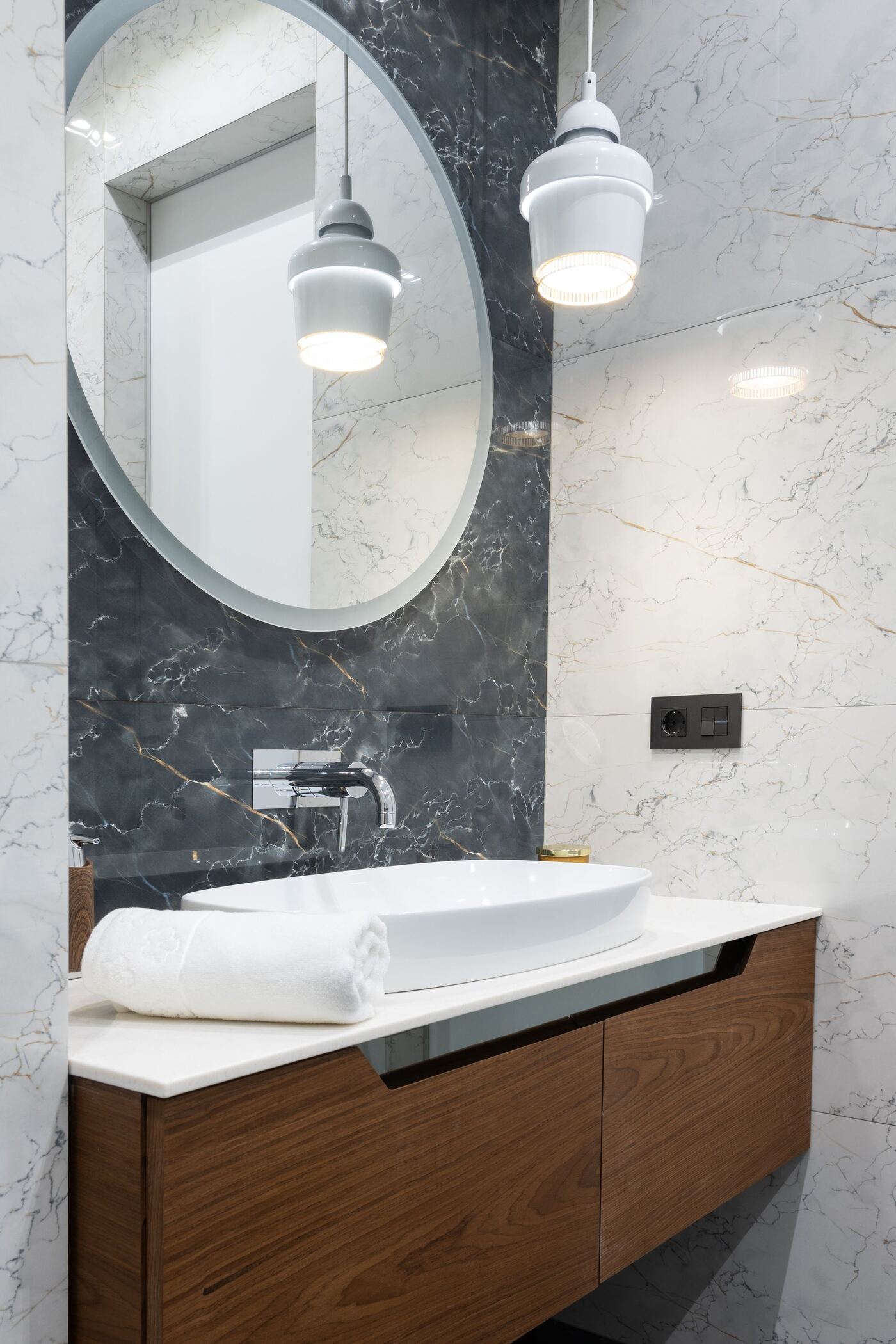 Lavabo de mármol con espejo ovalado y toallas