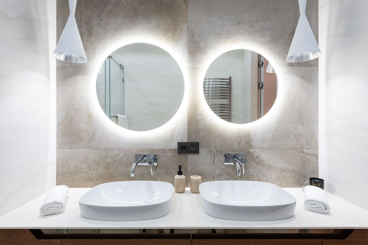 Baño con dos lavabos y espejos redondos iluminados